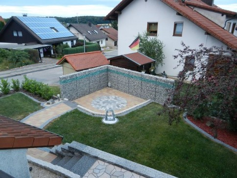 Fertige Terrasse mit beleuchtetem Gabionenaufbau